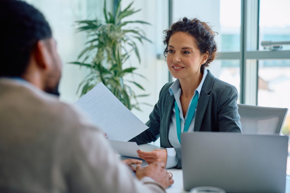 Deux professionnels en discussion dans un bureau moderne avec lumière naturelle et plante verte