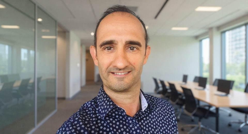 David Taillefer, souriant, dans un bureau moderne avec des murs vitrés et des bureaux équipés.