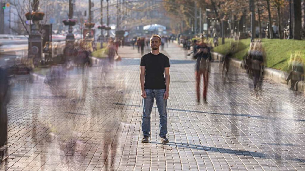 Homme immobile au milieu d’une rue bondée – image de la solitude dans la communication locale.