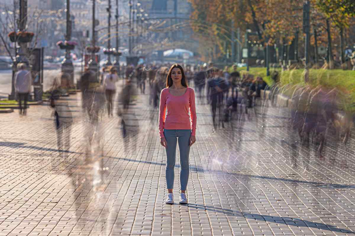 Jeune entrepreneuse seule au milieu d'une foule floue – symbole de l’isolement dans la communication locale.
